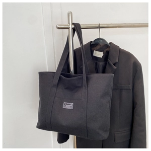 Close-up of black canvas tote bag with textured weave and fashion patch detail