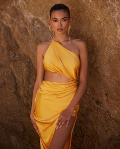 Detailed view of yellow satin one-shoulder dress with waist cutout and high split hem