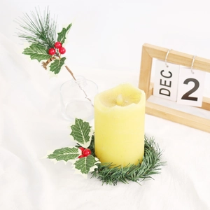Christmas candle ring with red berries and holly leaves next to a wooden advent calendar