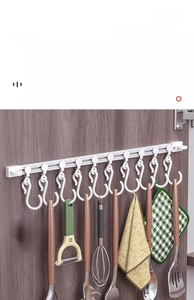 Close-up of sliding kitchen cabinet rail with hooks holding various cooking utensils