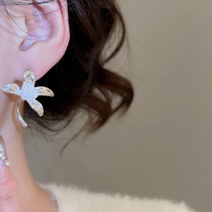 Nahaufnahme eleganter silberner Blumen-Ohrstecker mit matter Textur am Modell getragen
