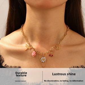 Detail of gold-plated necklace featuring dragonfly, daisy, heart, and cherry charms