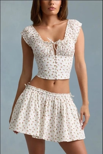 Detail of white floral crop top and skirt set with red print and drawstring neckline