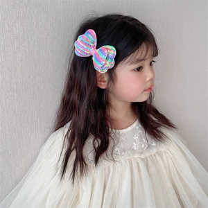 Detailed close-up of a rainbow sequin bow hair clip worn by a young girl on her hair