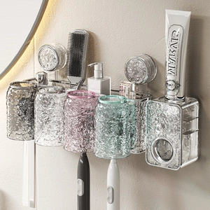 Wall-mounted suction toothbrush holder with four translucent cups and toothpaste dispenser