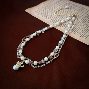 Close-up of double-layer necklace with Baroque pearls, pink stones, and a floral pendant