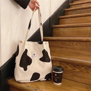 Close-up of corduroy tote bag with cow print pattern and white fabric label detail