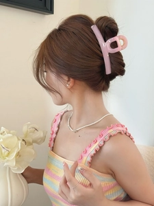 Detail of a large pink resin butterfly hair claw clip worn on hair with golden spring