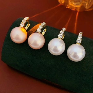 Detailed macro view of gold-plated earrings with pink and white pearls on velvet display