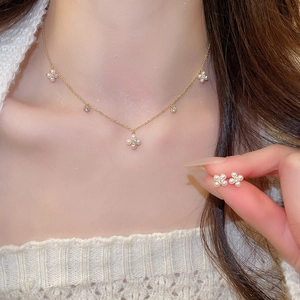 Elegant gold plated clover jewelry set with white pearls and sparkling zircons on model