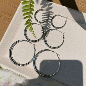 Detailed view of three pairs of silver hoop earrings in varying sizes on a beige tray