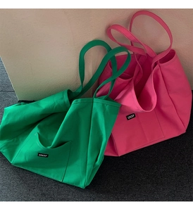 Close-up of green and pink canvas tote bags showing front pockets and durable straps