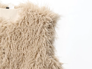 Macro detail of curly faux fur texture on a beige sleeveless vest for women
