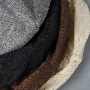 Detailed view of lightweight knitted hats showing openwork texture in neutral colors
