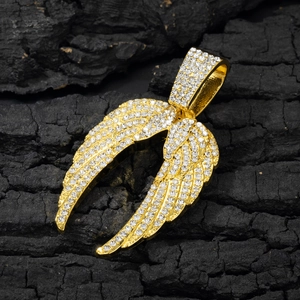 Gros plan détaillé du pendentif ailes d'ange dorées serti de strass sur bois noir
