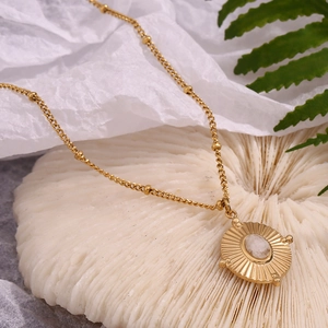 Macro shot of 18K gold plated oval necklace featuring natural white crystal on textured background