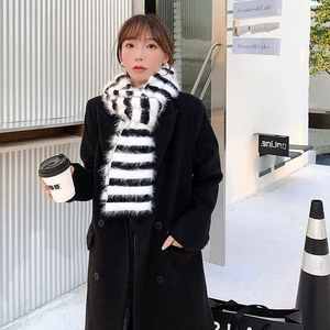 Detail of soft black and white striped scarf with long handmade tassels on a city street