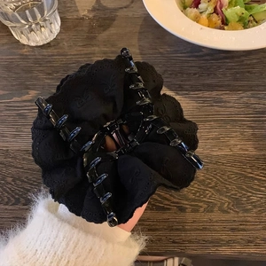 Close-up of elegant black lace hair claw clip with embroidered bows and ruffled edges