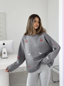 Detailed close-up of grey crewneck sweater featuring dachshund dog embroidery and ribbed cuffs