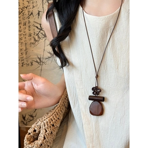 Detail of vintage Maillard wood resin geometric pendant on long sweater chain