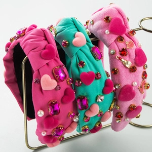 Close-up of pearl heart headbands in rose, blue and pink on a gold metal stand
