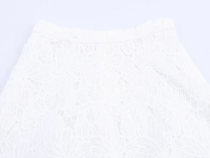 Close-up detail of white lace skirt waistband featuring floral hollow embroidery texture