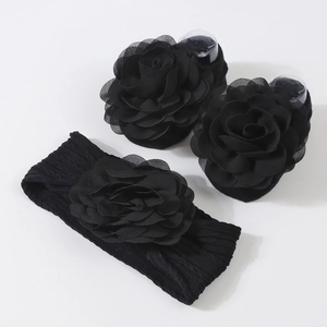 Détail de chaussettes noires pour bébé et bandeau assorti avec fleur en gaze douce