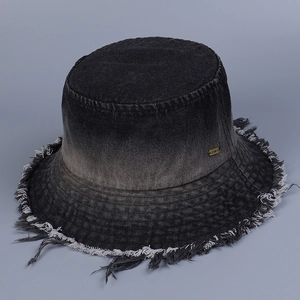 Detailed view of gradient denim bucket hat featuring frayed edges and gold metal tag