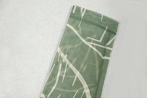 Detailed close-up of green mesh fabric with white floral patterns and soft texture
