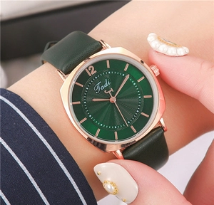 Detail of a square green ripple dial watch with gold case on a female wrist