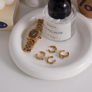 Elegant gold vintage watch and sparkling zircon ring set on a white decorative tray