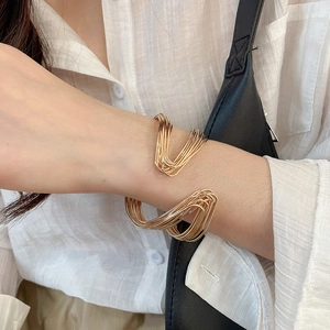 Detail shot of a minimalist gold twisted layered open cuff bracelet worn by a model