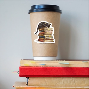 Close-up of holographic black cat and book stack sticker on a wooden coffee mug