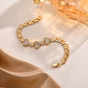 Detail shot of golden heart bracelet with white zircon stones on silk background