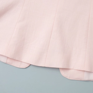 Gros plan de l'ourlet de veste rose pâle avec coupe arrondie et coutures fines de précision