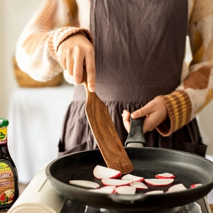 Teak wood spatula stirring food in a frying pan for professional kitchen cooking