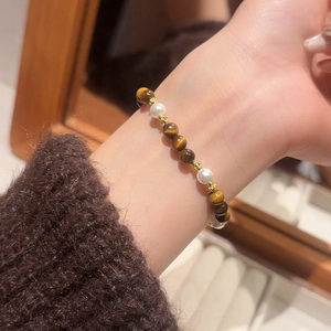 Detail of beaded bracelet with tiger eye stones and pearls on a plush brown cuff