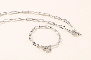 Close-up of silver paperclip chain necklace and bracelet set with toggle clasp detail