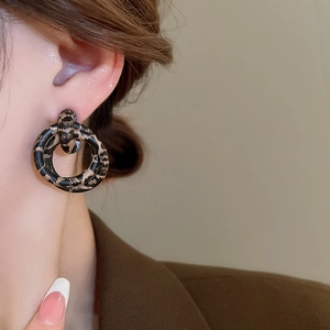 Close-up of model wearing retro leopard print double hoop earrings with a glossy finish