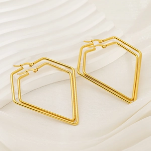 Close-up of golden geometric double-layered pentagon earrings on textured surface