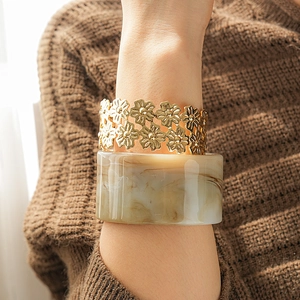 Detail of vintage gold flower cuff paired with marble resin bangle on sweater sleeve