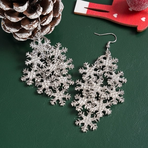 Detailed close-up of silver snowflake earrings with crystals on festive green leather