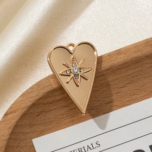 Golden heart pendant with starburst engraving and white rhinestone on silk