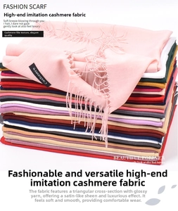 Close-up of stacked cashmere-feel scarves in various colors showing fringes and labels
