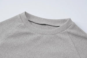 Dettaglio della trama in maglia a costine grigia sulla spalla del top crop aderente