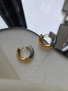 Close-up of chunky two-tone gold and silver polished stainless steel hoop earrings