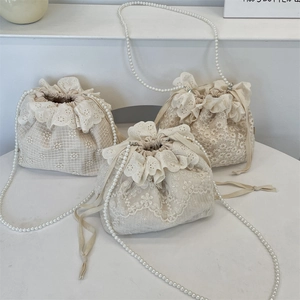 Three ivory lace drawstring bucket bags with floral embroidery and pearl chain straps