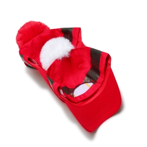 Close-up of red Christmas Santa hat with large white faux fur pompom and striped detail