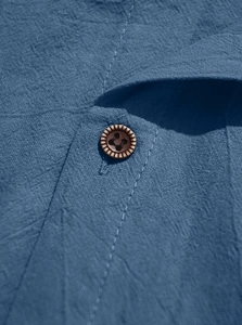 Macro shot of the indigo cotton shirt neckline with textured fabric and wooden button