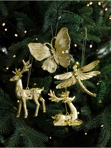 Close-up of gold electroplated deer and insect ornaments on a green Christmas tree